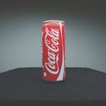A classic Coca-Cola can showcased on a dark surface with minimal lighting.